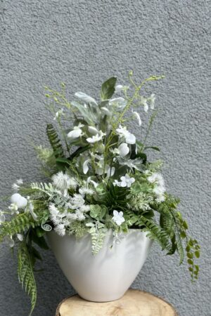 Kompozycja w białym matowym ceramicznym naczyniu z wykorzystanie białej i zielonej roślinności traw, ostów, paproci, storczyka.