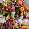 Jesienny wianek wykonany na wiklinowym kole z dodatkiem jesiennych liści, owoców, dyń, grzybów i kwiatów,