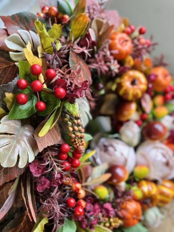 Jesienny wianek wykonany na wiklinowym kole z dodatkiem jesiennych liści, owoców, dyń, grzybów i kwiatów,