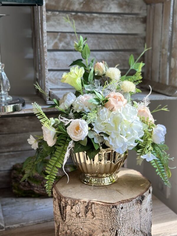 Kompozycja sztuczna wykonana w złotej szkliwionej ceramicznej podstawie z dodatkiem kwiatów hortensji, eustomy, peoni i różyczki.
