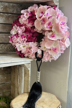 Wianek wykonany z różowych kwiatów satynowych hortensji oraz silikonowego storczyka. Dekoracja została dopełniona czarno-srebrnym chwostem.