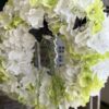 Wianek wykonany z sztucznych kwiatów biało zielonej hortensji. Dodatkiem czarne motyle oraz zielony zwis.