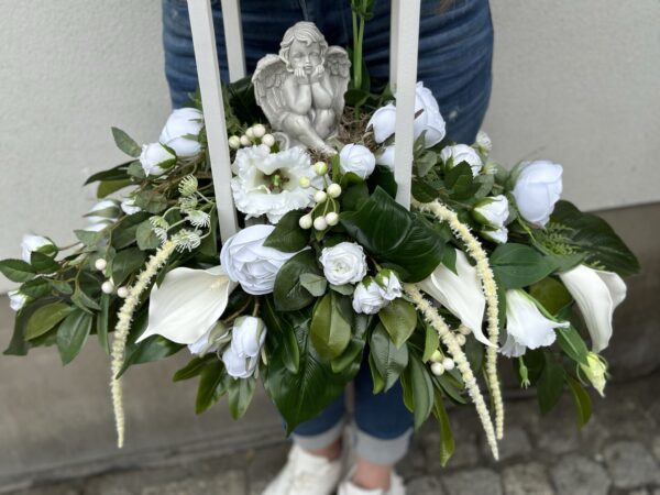 Kompozycja nagrobna wykonana w drewnianym lampionie z gipsowym aniołkiem i białymi kwiatami.
