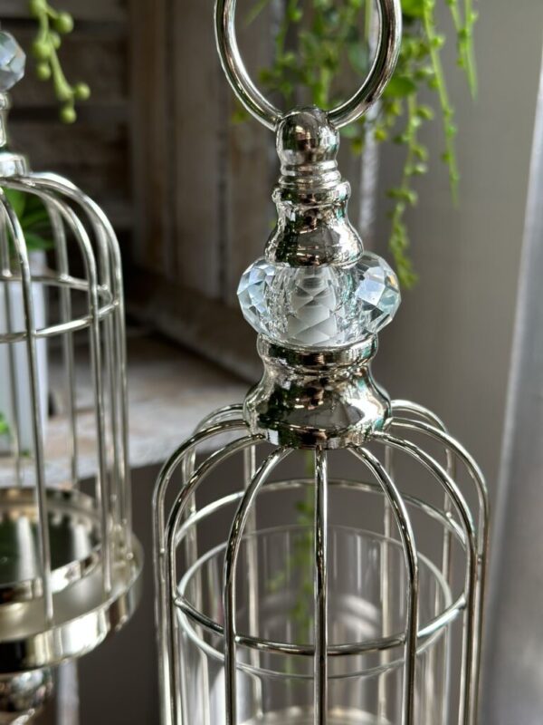 Świecznik metalowy w srebrnym kolorze w kształcie klatki z dodatkiem akrylowej kuli.