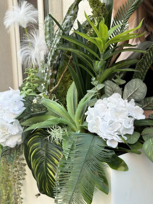 Kompozycja kwiatowa w podłużnej białej plastikowej osłonce